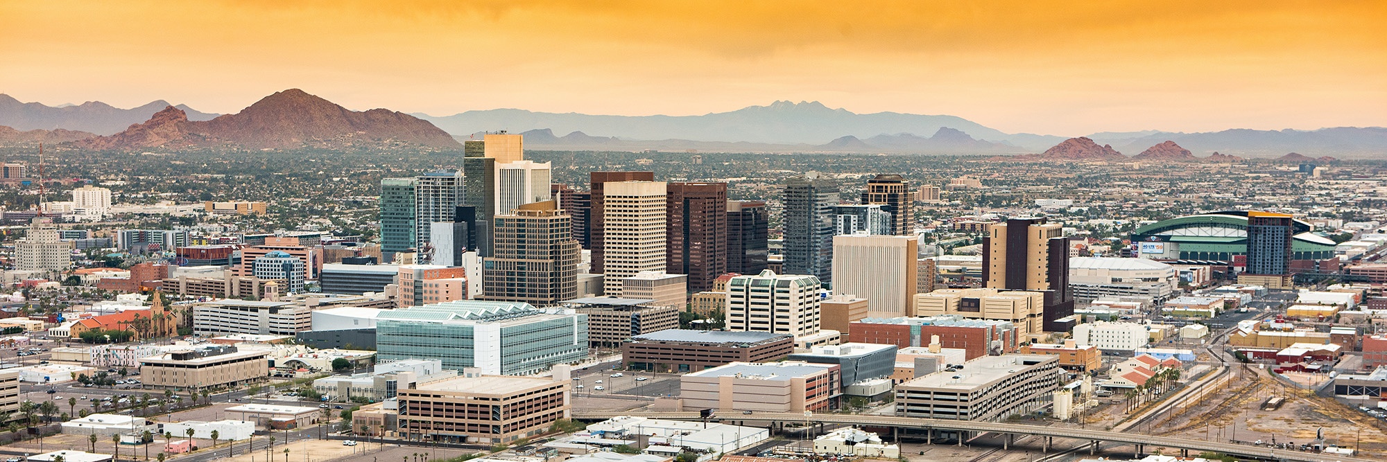 Panoramic aerial view of the Phoenix, Arizona skyline against the day's blue sky.